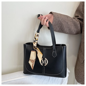 Close-up of black leather tote with gold M logo, white contrast stitching and silk scarf