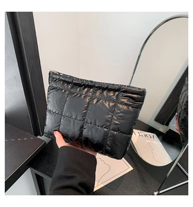 Détail de la pochette matelassée noire brillante avec fermeture éclair dorée chic