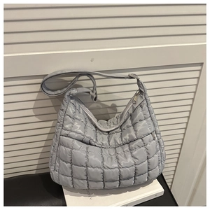 Détail du sac matelassé gris clair avec texture bouffante et fermeture éclair