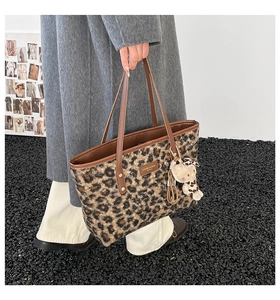 Detail shot of leopard print tote bag with brown leather straps and cute plush charm