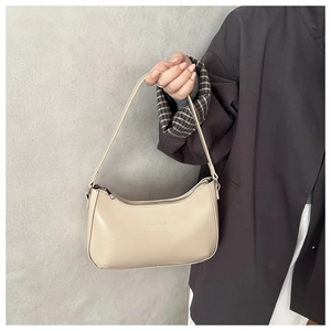 Detailansicht der cremefarbenen PU-Schultertasche mit Fashion & Bags Text und feiner Narbung