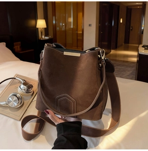 Detail of dark brown suede bucket bag with retro stitching and gold hardware accent
