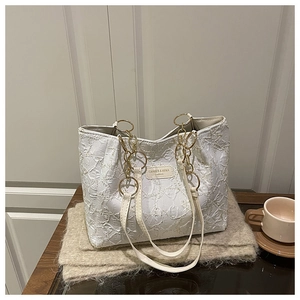 Détail d'un sac cabas blanc matelassé avec chaînes dorées et coutures texturées élégantes