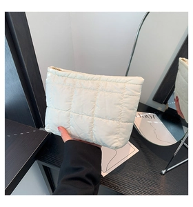 Détails d'une pochette matelassée blanche avec fermeture éclair et texture plissée
