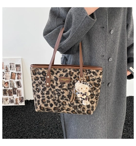 Detail view of leopard print tote bag with brown leather handles and brand logo tag