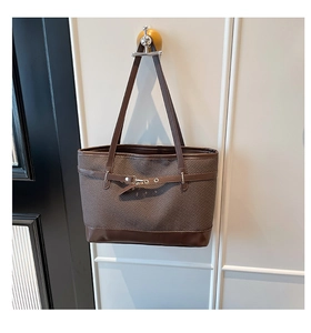 Detailed view of dark brown woven tote bag featuring smooth leather handles and metal buckles