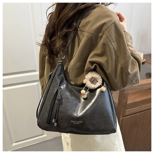 Detailansicht einer schwarzen Leder-Hobo-Tasche mit Fransen-Reißverschluss und Schaf-Anhänger