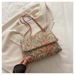 Details des floralen Jacquard-Stoffs und der Metallkette einer Vintage-Schultertasche