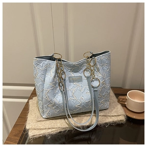 Gros plan du sac cabas bleu clair avec texture matelassée en étoile et chaîne en métal