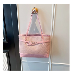 Detail of pink woven tote bag with smooth leather straps and metal buckle accents