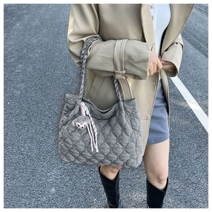 Detail of grey quilted tote bag with woven handle and purple plush bunny charm