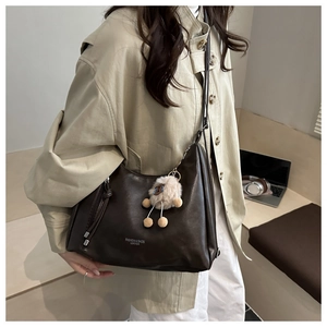 Nahaufnahme der braunen Retro-Schultertasche mit Quastendetail und Plüsch-Schaf-Anhänger