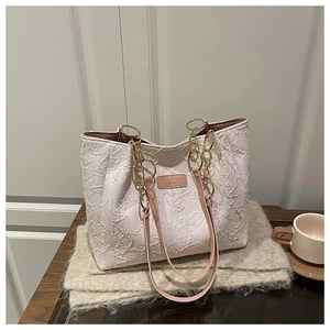 Détail du sac cabas blanc à texture étoilée avec chaîne dorée et bandoulière rose