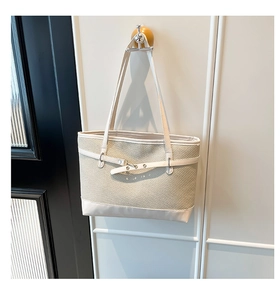 Detail of minimalist cream woven tote bag with white faux leather trim and buckle strap