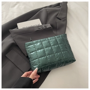 Détail d'une pochette matelassée vert foncé en nylon brillant sur un blazer gris