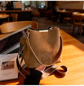 Detailed view of brown matte bucket bag texture with gold hardware in cozy cafe setting
