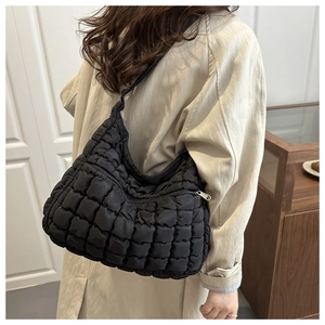 Détail du sac cabas noir matelassé avec texture plissée porté sur un trench-coat