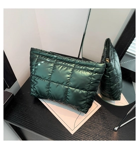 Détail d'une pochette matelassée vert foncé avec fini brillant et zip doré