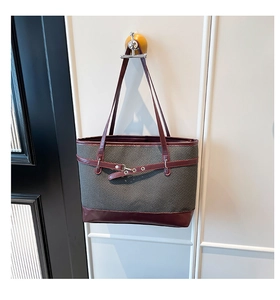 Close-up of gray herringbone fabric tote bag with burgundy leather trim and silver buckles