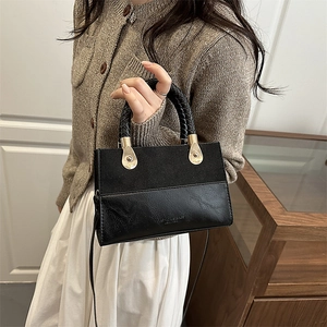Retro black crossbody bag with woven handle and gold hardware on minimalist daily outfit