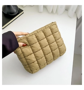 Makro-Detail der khakifarbenen gesteppten Clutch mit Gittermuster und gepolsterter Textur