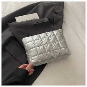 Détail d'une pochette matelassée argentée avec texture métallique et fermeture éclair