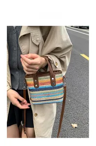 Detail of colorful woven straw bucket bag with brown faux leather straps and silver buckles