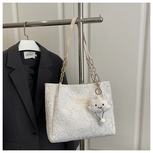 Détail du sac cabas blanc à texture étoilée, chaîne dorée et breloque nuage peluche