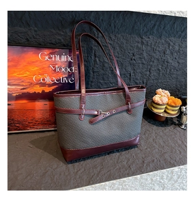 Detail of grey herringbone tote bag with wine red leather handles and metal eyelet straps