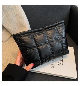 Détail de la pochette matelassée noire avec finition brillante et fermeture éclair