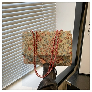 Detailansicht der Vintage-Blumenstickerei und des roten Lederkettenriemens der Tasche
