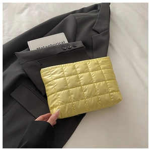 Détail d'une pochette matelassée jaune sur le fond d'un blazer gris élégant