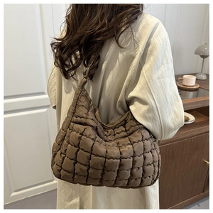 Sac hobo matelassé marron foncé porté à l'épaule dans un décor d'intérieur moderne