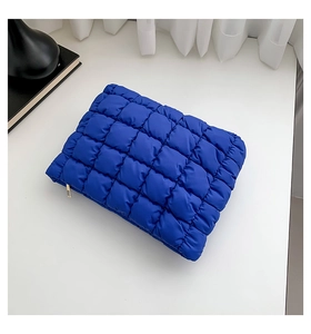 Makro-Detail der königsblauen gesteppten Kosmetiktasche mit Puffer-Textur und Reißverschluss