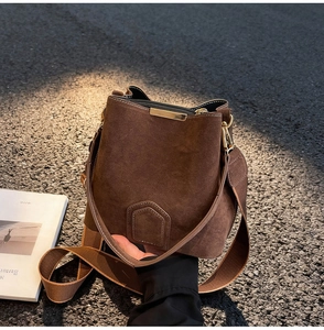 Detailed view of dark coffee suede bucket bag with shield stitching and gold trim