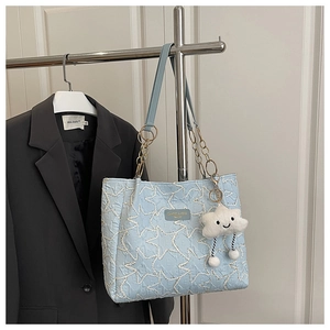 Détail du sac cabas bleu ciel avec surpiqûres en étoile, chaîne et pendentif nuage