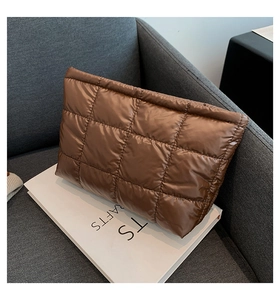 Détail d'un sac à main matelassé marron café sur un canapé gris avec finition satinée