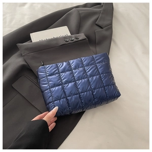 Détail d'un sac à main matelassé bleu foncé avec coutures carrées et fermeture éclair