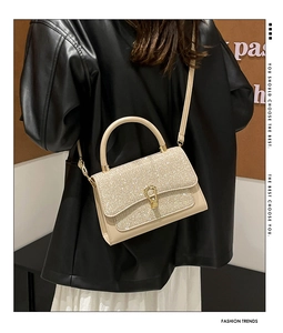 Detail of a chic cream-colored handbag with silver sequin flap and metal horseshoe buckle