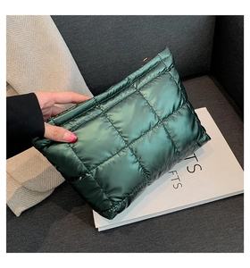 Détail d'une pochette matelassée vert foncé avec finition métallisée et fermeture éclair