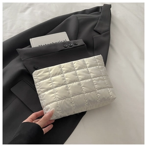 Détail de pochette en nylon blanc matelassé avec texture rembourrée et zip noir sur veste