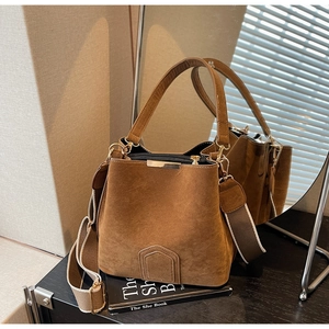 Detail of brown matte bucket bag showing the soft texture and wide fabric shoulder strap