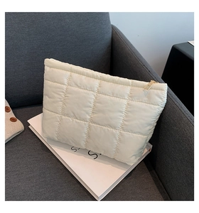 Détail d'une pochette matelassée blanche en nylon avec fermeture éclair dorée