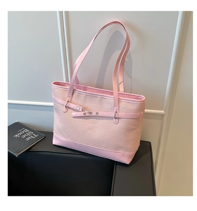 Close-up of pink woven tote bag with faux leather strap and buckle detail on white backdrop
