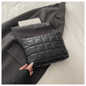 Gros plan sur la texture matelassée noire et la fermeture éclair de la pochette de soirée