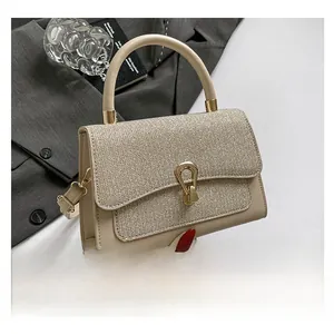 Detailed close-up of champagne glitter textured handbag with elegant gold horseshoe clasp