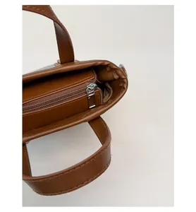 Detailed macro view of the brown leather bucket bag inner zip pocket and silver zipper