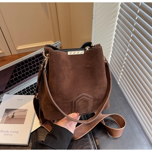 Detail of dark brown suede bucket bag with gold hardware and stylish woven shoulder strap