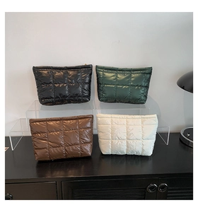 Détail de trousses de maquillage matelassées en noir, vert, marron et beige avec zip doré