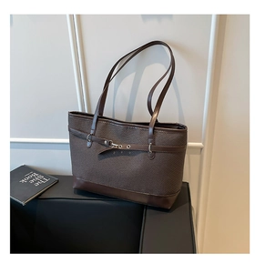 Detail of dark brown tote bag featuring woven texture and smooth leather trim finish